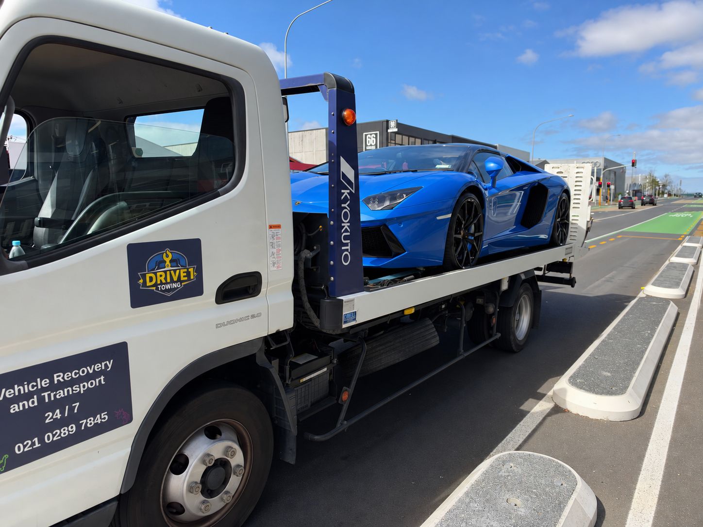 Blue Lamborghini on the back of a white Drive1 Towing truck; body colour digitally changed for privacy.