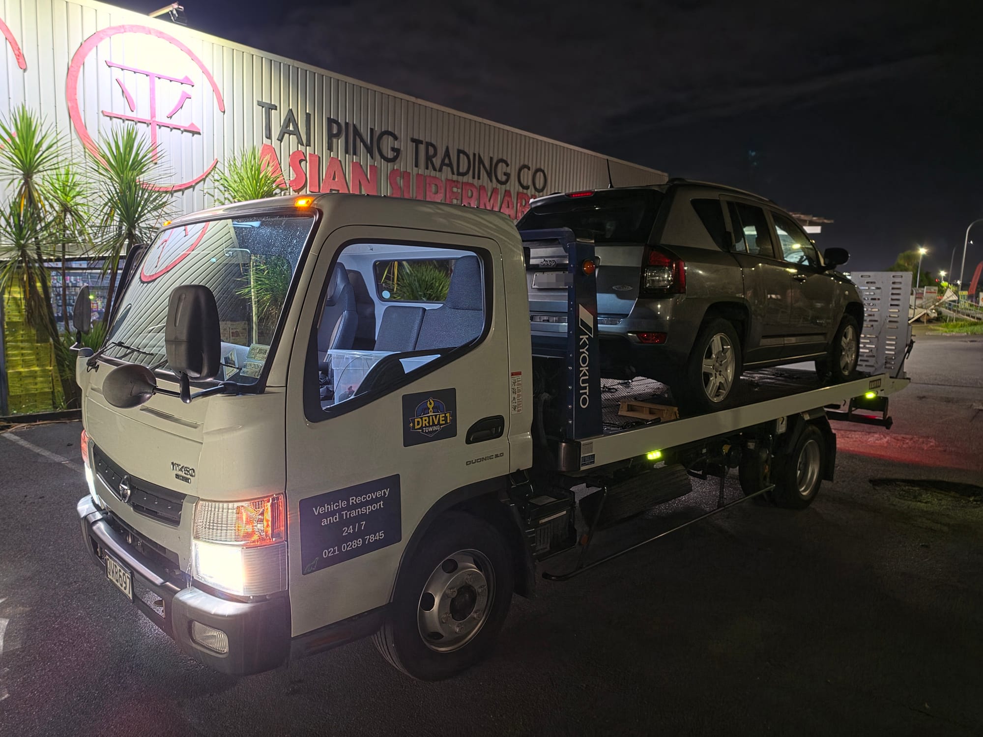 Drive1 Towing flatbed loaded with an SUV at night in Wairau Valley, Auckland.
